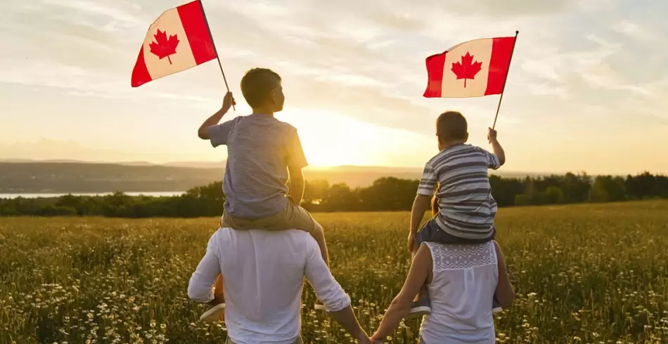 أبوين يحملون أطفالهم الذين يرفعون علم كندا